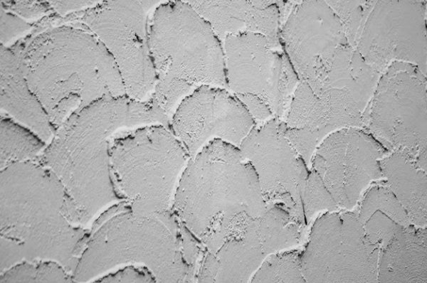 Текстура декоративной штукатурки на фоне штукатурки грубо нанесена на стену в виде полукругов